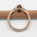 Side view of rose gold ring with milgrain detail and openwork under the green sapphire setting