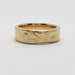Side view of a 14k yellow gold wedding band with a rough hand-carved texture