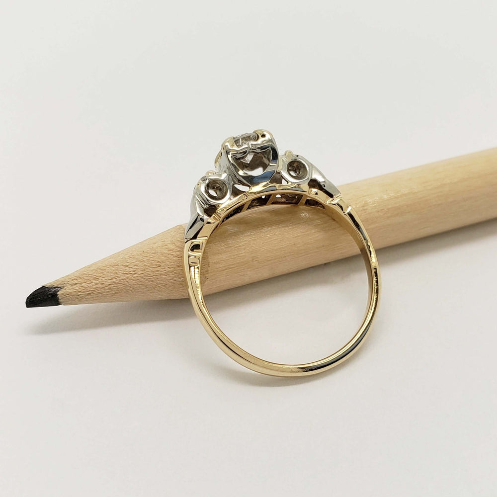 Side view of two-tone diamond engagement ring on a pencil showing band and setting