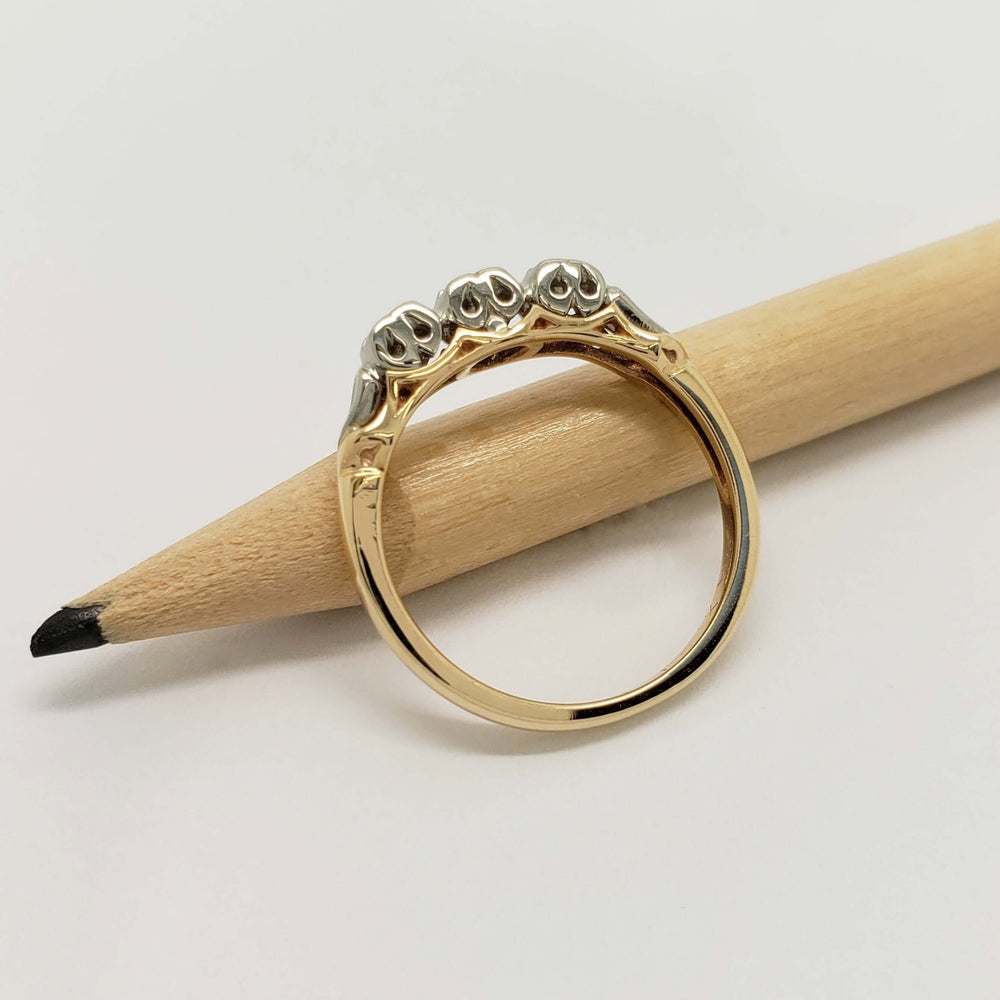 Side view of two-tone diamond wedding ring in yellow and white gold, resting on a pencil