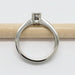 Side view of white gold engagement ring with moissanite, resting on a pencil