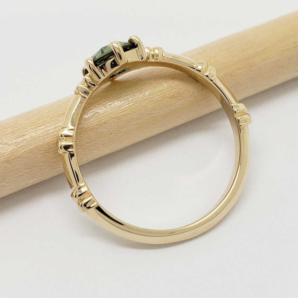 Side view of yellow gold engagement ring with green sapphire and floral details