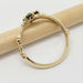 Side view of yellow gold engagement ring with green sapphire and floral details