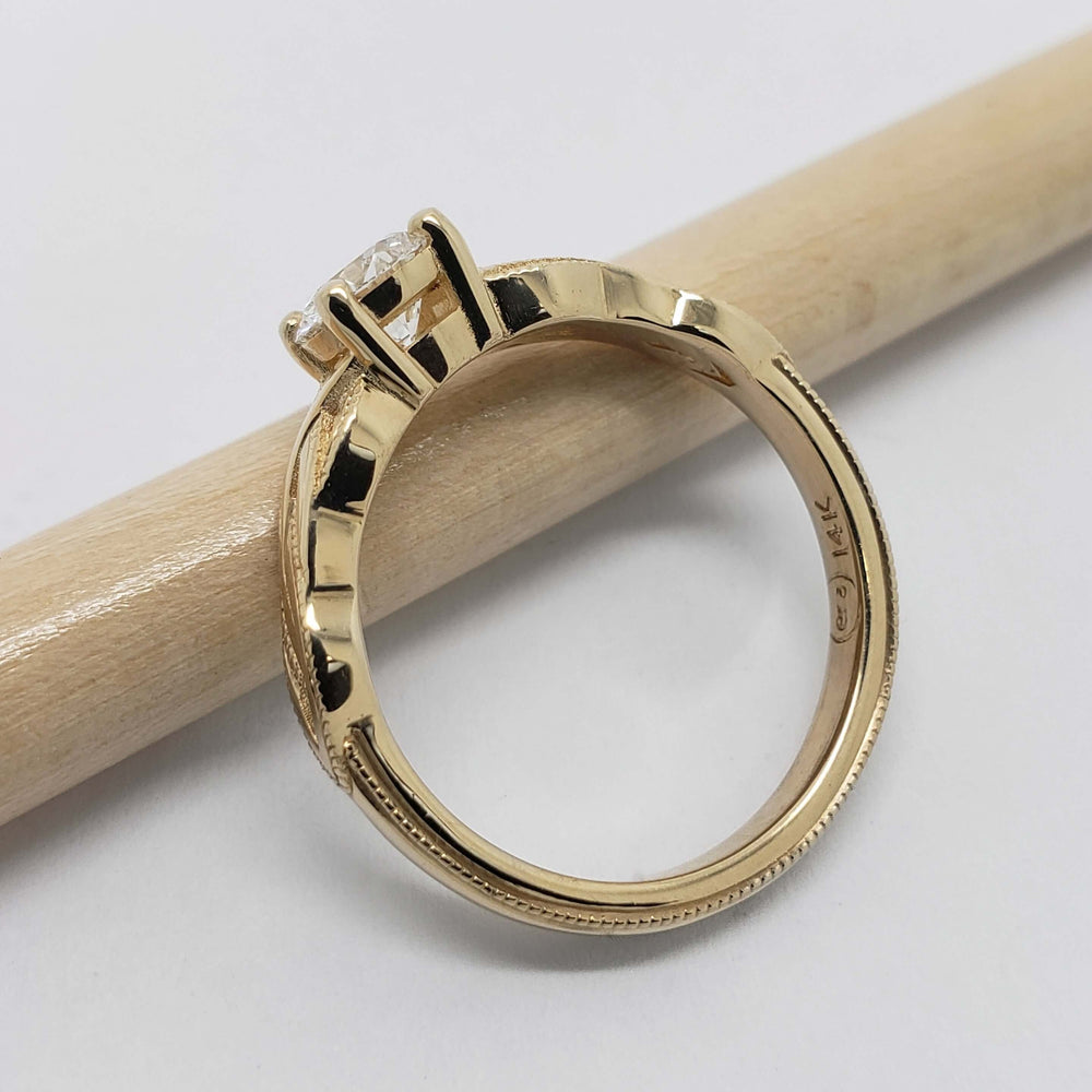 Side view of yellow gold engagement ring with millgrain detail and round lab diamond