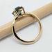 Side view of yellow gold ring with cushion cut green sapphire on a pencil