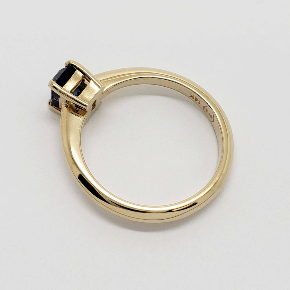 Side view of yellow gold ring with emerald cut blue Montana sapphire