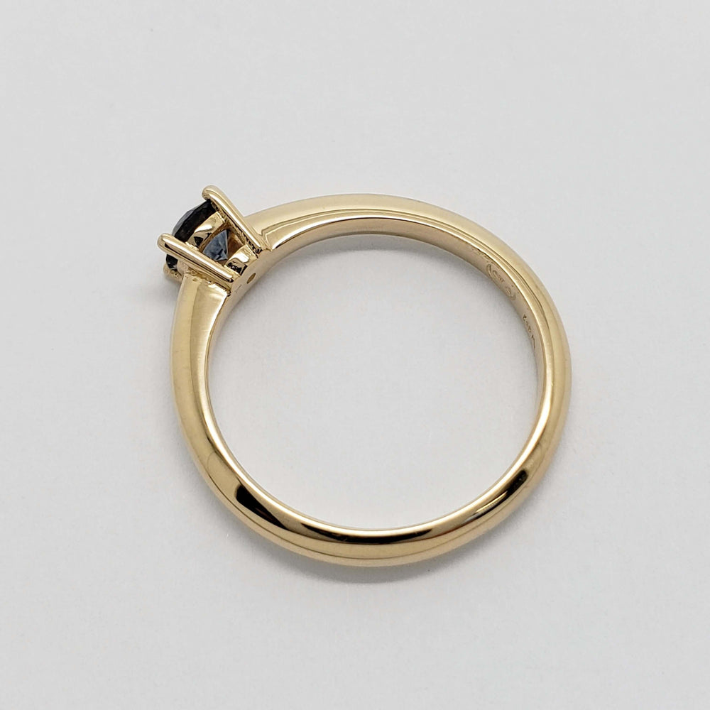 Side view of yellow gold ring showing prong-set blue Montana sapphire
