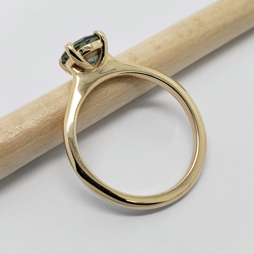 Side view of yellow gold ring with teal Australian sapphire and four-prong setting