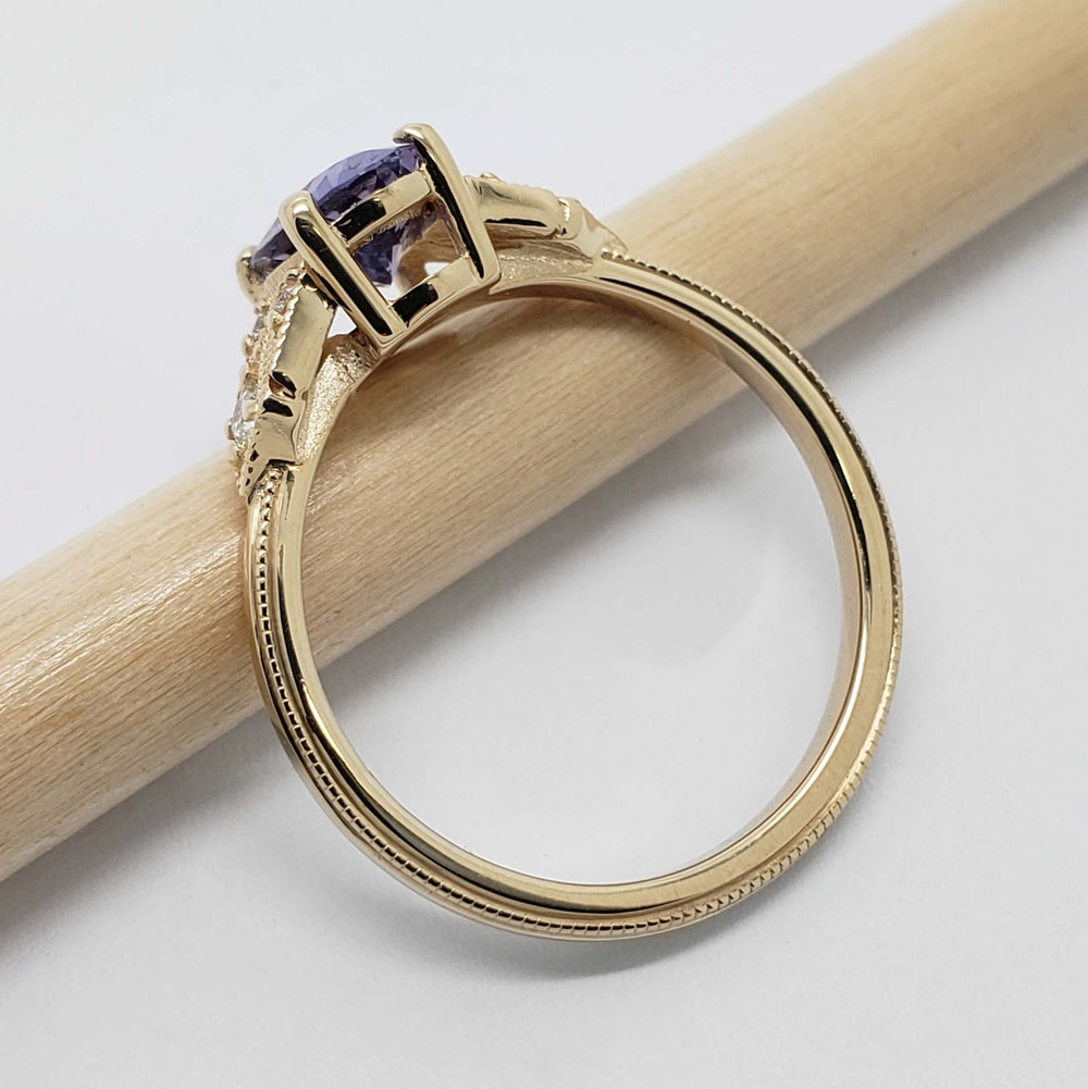 Side profile of 14kt yellow gold ring with oval sapphire and diamond accents