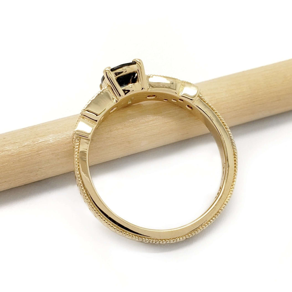Side view of yellow gold sapphire and diamond engagement ring resting on a pencil