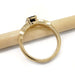 Side view of yellow gold sapphire and diamond engagement ring resting on a pencil