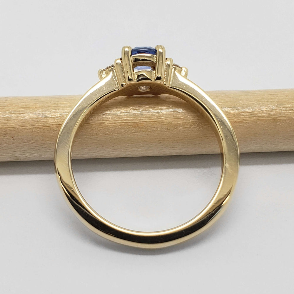 Side profile of yellow gold ring with blue sapphire and diamond accents