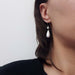 Simulated opal dangle earring in 14kt white gold worn on ear