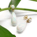 Simulated opal drop earrings in 14kt yellow gold displayed on a green leaf