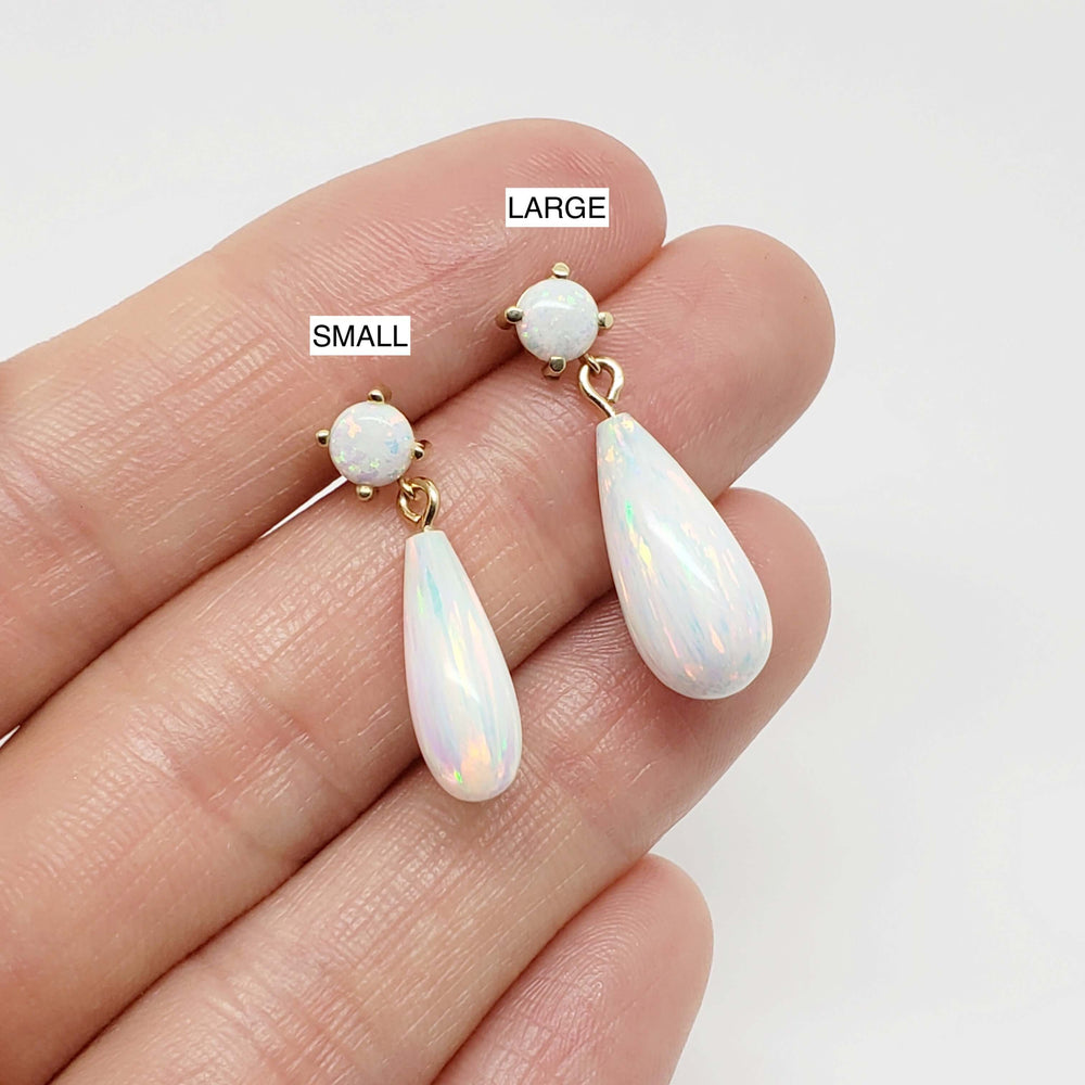 Comparison of small and large simulated opal drop earrings in 14kt yellow gold, held in hand