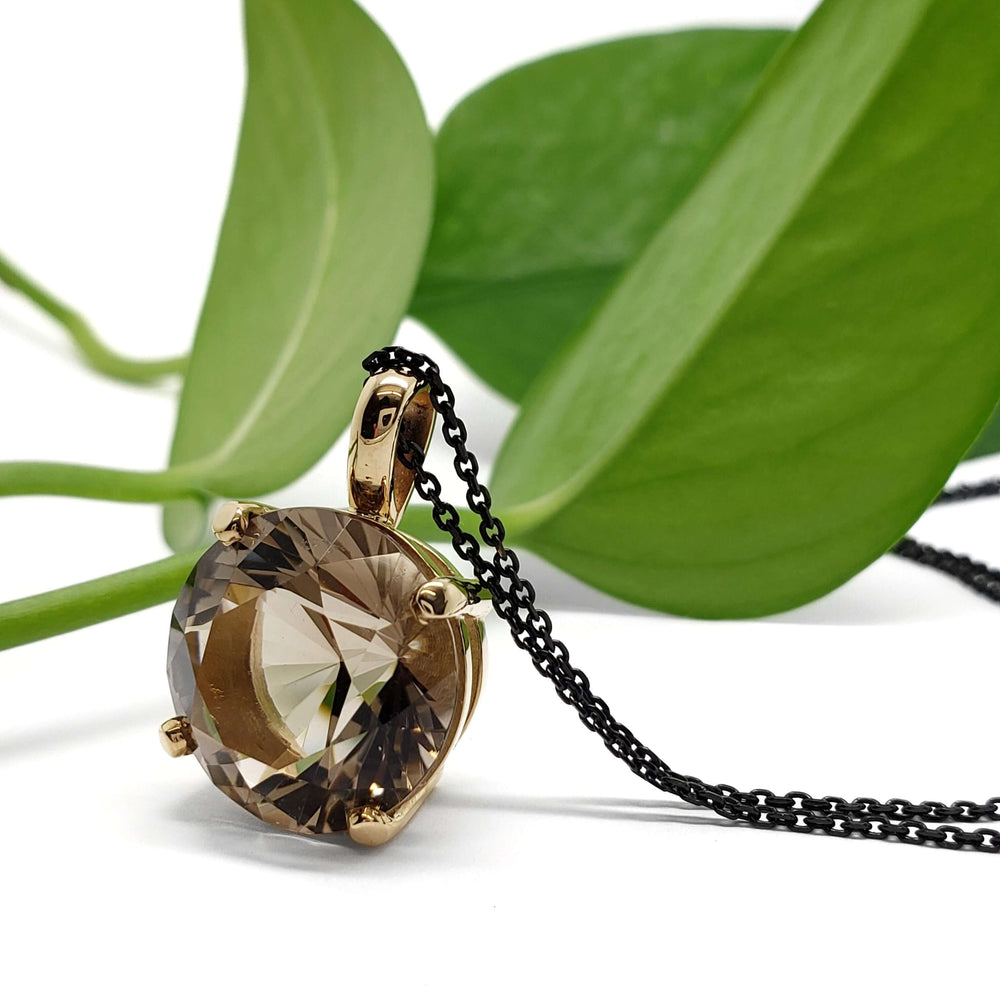Smoky quartz and 14kt yellow gold pendant with black chain, styled with green leaves