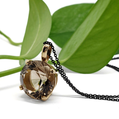 Smoky quartz and 14kt yellow gold pendant with black chain, styled with green leaves