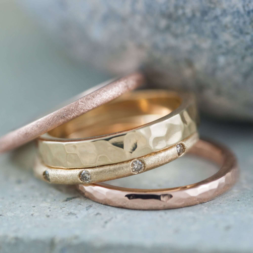 Stack of gold and rose gold wedding bands, including a champagne diamond band