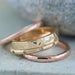 Stack of gold and rose gold wedding bands, including a champagne diamond band