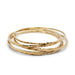 Stack of handcrafted 14kt yellow gold hammered bangles on white background