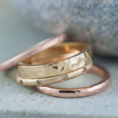 Stack of textured and hammered gold wedding bands, including rose gold ring