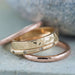 Stack of textured and hammered gold wedding bands, including rose gold ring