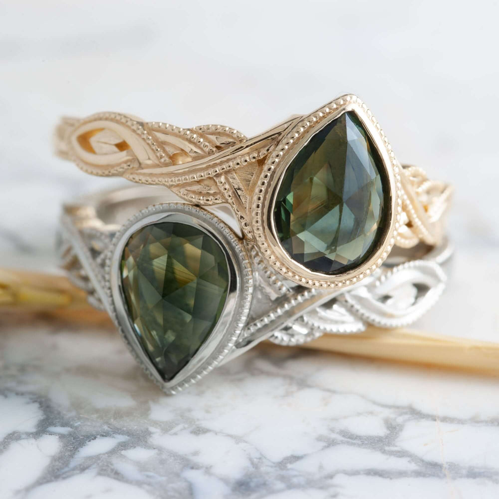 Stacked green sapphire engagement rings in white and yellow gold with intricate interlace bands