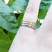 Stack of yellow, white, and rose gold millgrain rings on a hand