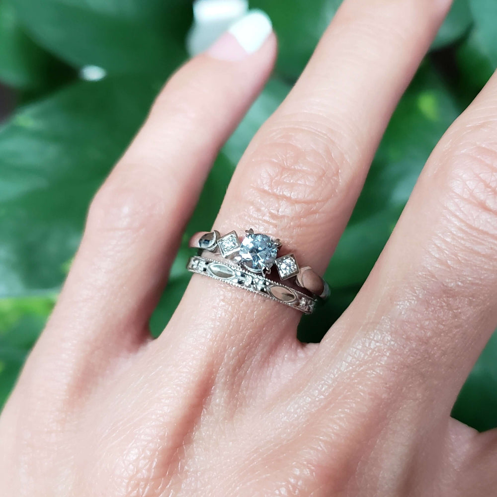 Stacked white gold floral wedding ring and diamond engagement ring on finger