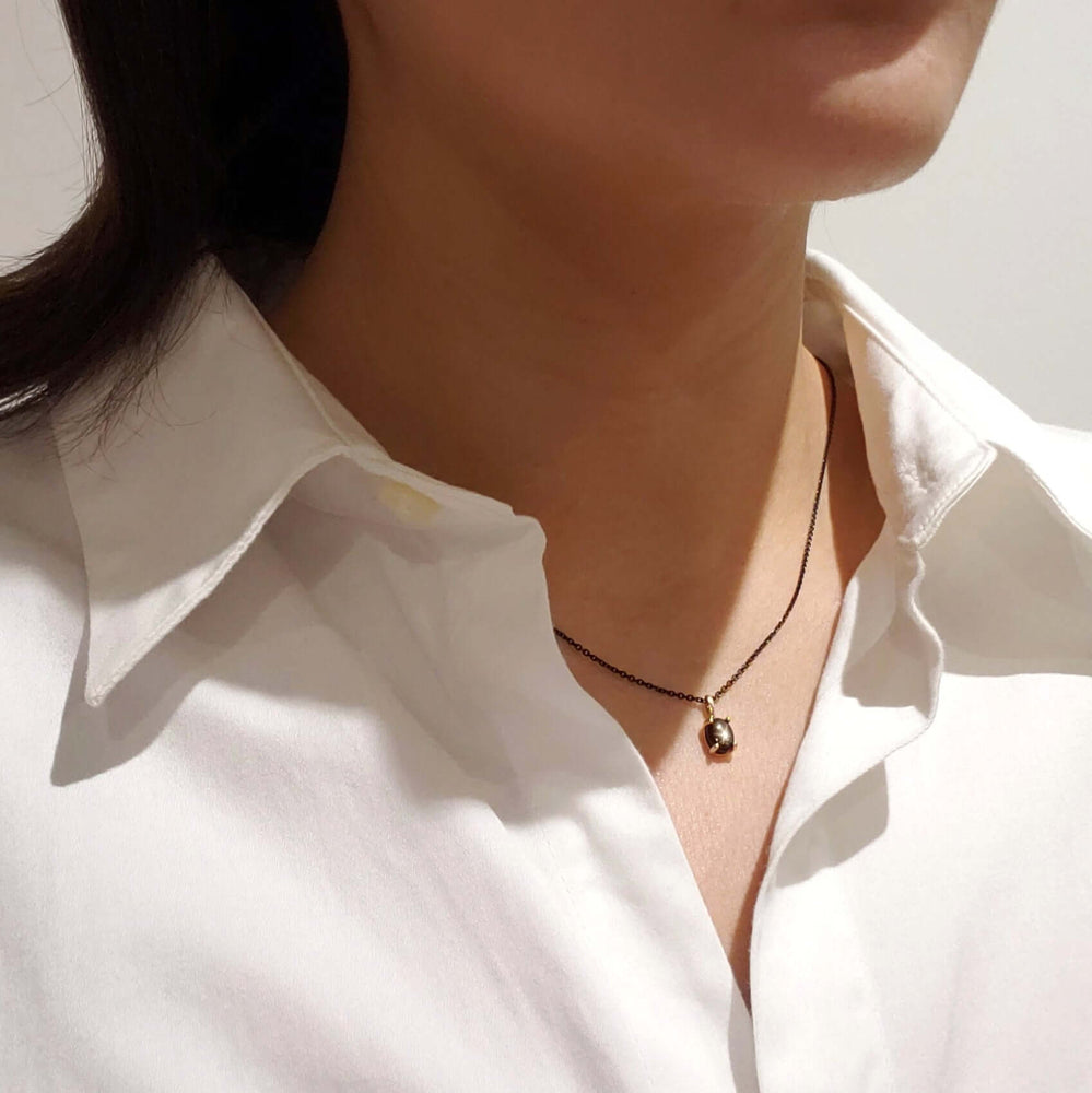 Star sapphire pendant in yellow gold on black chain, worn at the neck