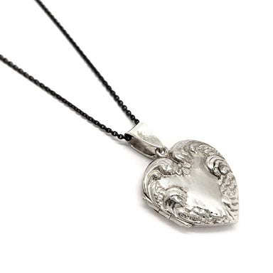 Sterling silver heart-shaped locket with ornate floral engraving on a chain