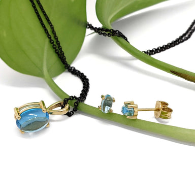 Swiss blue topaz pendant and matching 14kt yellow gold stud earrings on green leaf