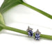 Tanzanite and diamond 10kt white gold stud earrings displayed on a green stem