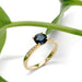 Teal Australian sapphire and diamond engagement ring in yellow gold, styled with green leaves