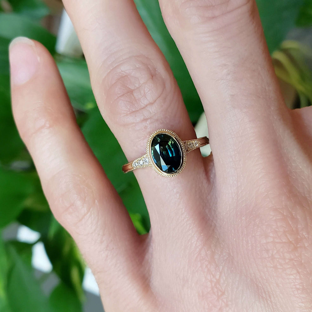Teal Australian sapphire and diamond yellow gold ring worn on hand