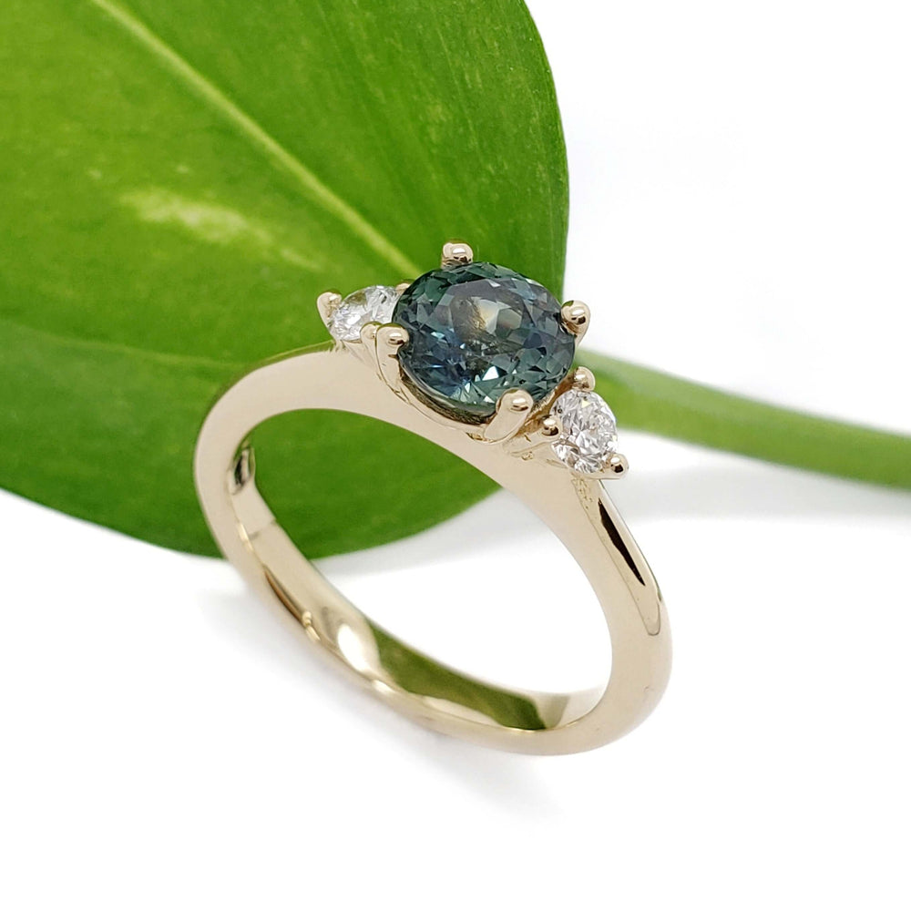 Teal Australian sapphire and lab diamond ring in yellow gold, shown with green leaf