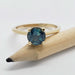 Teal Australian sapphire ring in yellow gold shown with a pencil for scale