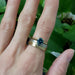 Teal Australian sapphire ring in yellow gold stacked with wide mixed-metal band on hand