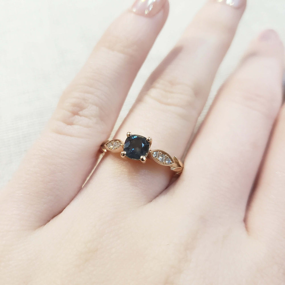 Teal Montana sapphire and diamond engagement ring in rose gold shown on hand