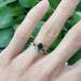 Teal Montana sapphire engagement ring stacked with a white gold leaf band, worn on hand