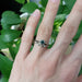 Teal sapphire and diamond engagement ring stacked with a leaf motif band on hand