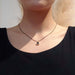 Teal tourmaline bezel pendant in 14kt yellow gold worn on a black chain, shown on model