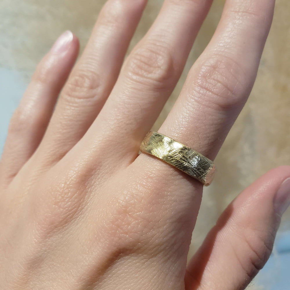 Textured 14k yellow gold wedding band shown on a hand