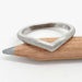 Textured 14kt white gold chevron wedding band resting on a pencil