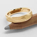 Textured 14kt yellow gold wedding ring resting on a pencil, close-up