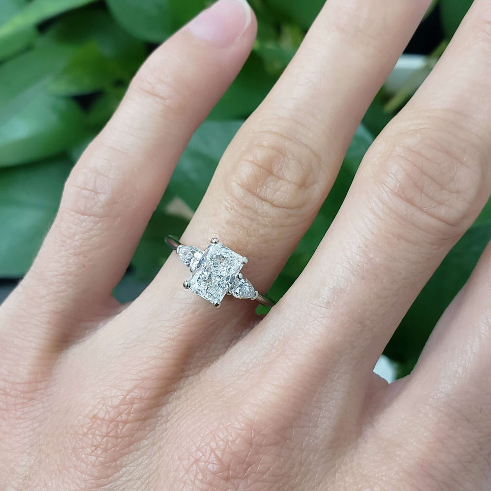 Three-stone lab diamond engagement ring in white gold worn on a hand