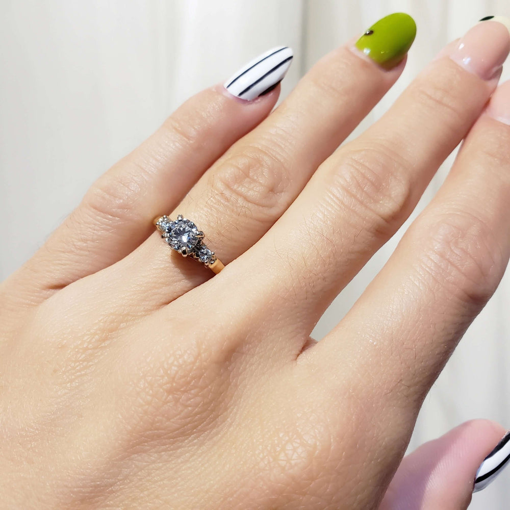 Three-stone vintage diamond ring in yellow and white gold shown on hand