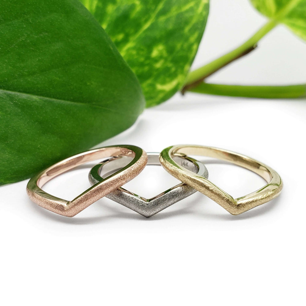 Three chevron wedding rings in 14kt rose, white, and yellow gold with saw blade texture