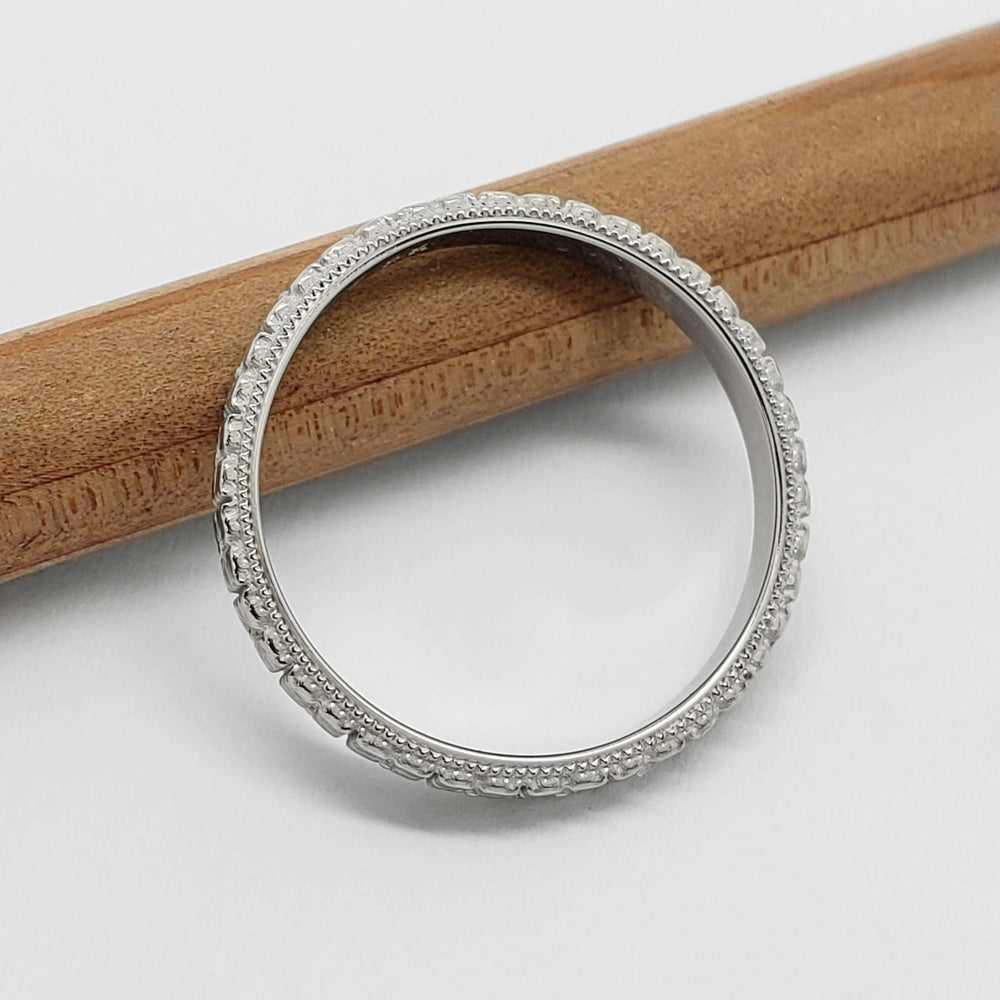 Top view of 14kt white gold wedding ring with floral and millgrain details