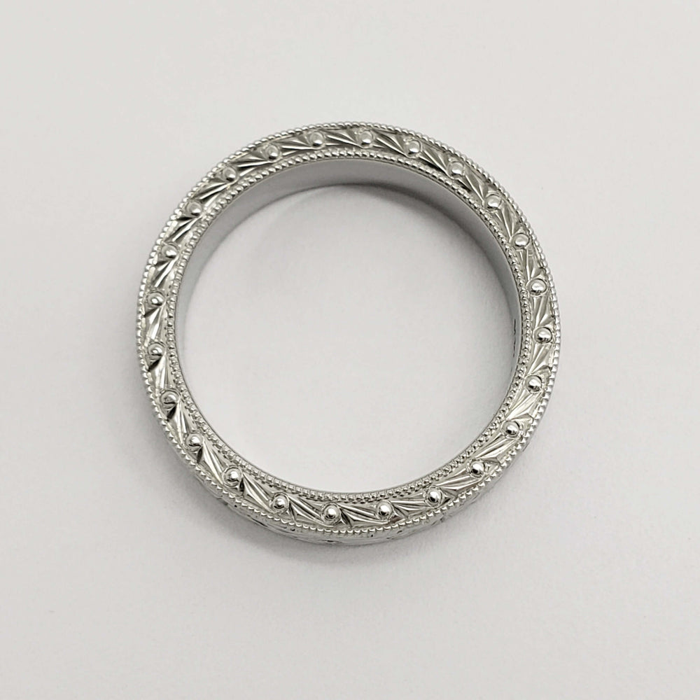 Top view of engraved 14kt white gold wedding ring with millgrain detail